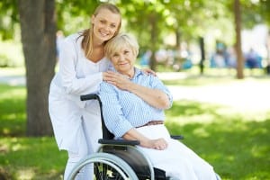 Pretty nurse and senior patient in a wheelchair looking at camer